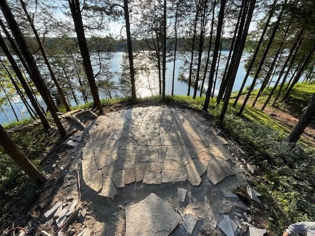 A person is standing in the middle of a forest overlooking a lake.