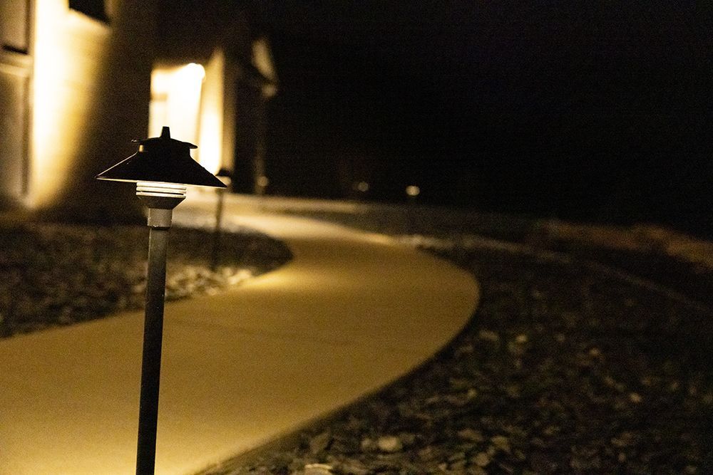 A path with a light on the side of it at night.