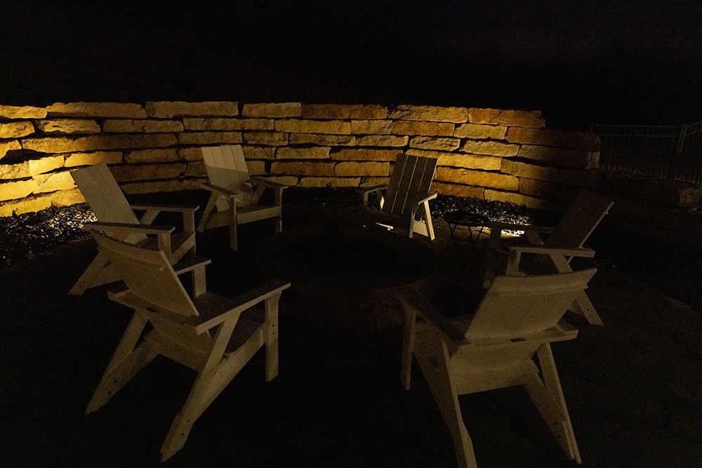 A group of chairs are sitting in front of a brick wall at night.