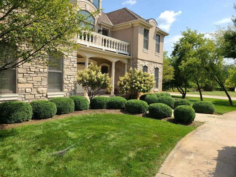 A large house with a lush green lawn and bushes in front of it.
