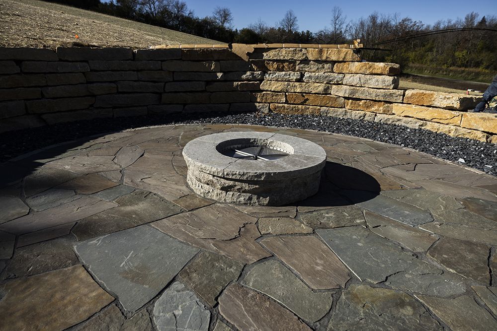 A fire pit is sitting in the middle of a stone patio.