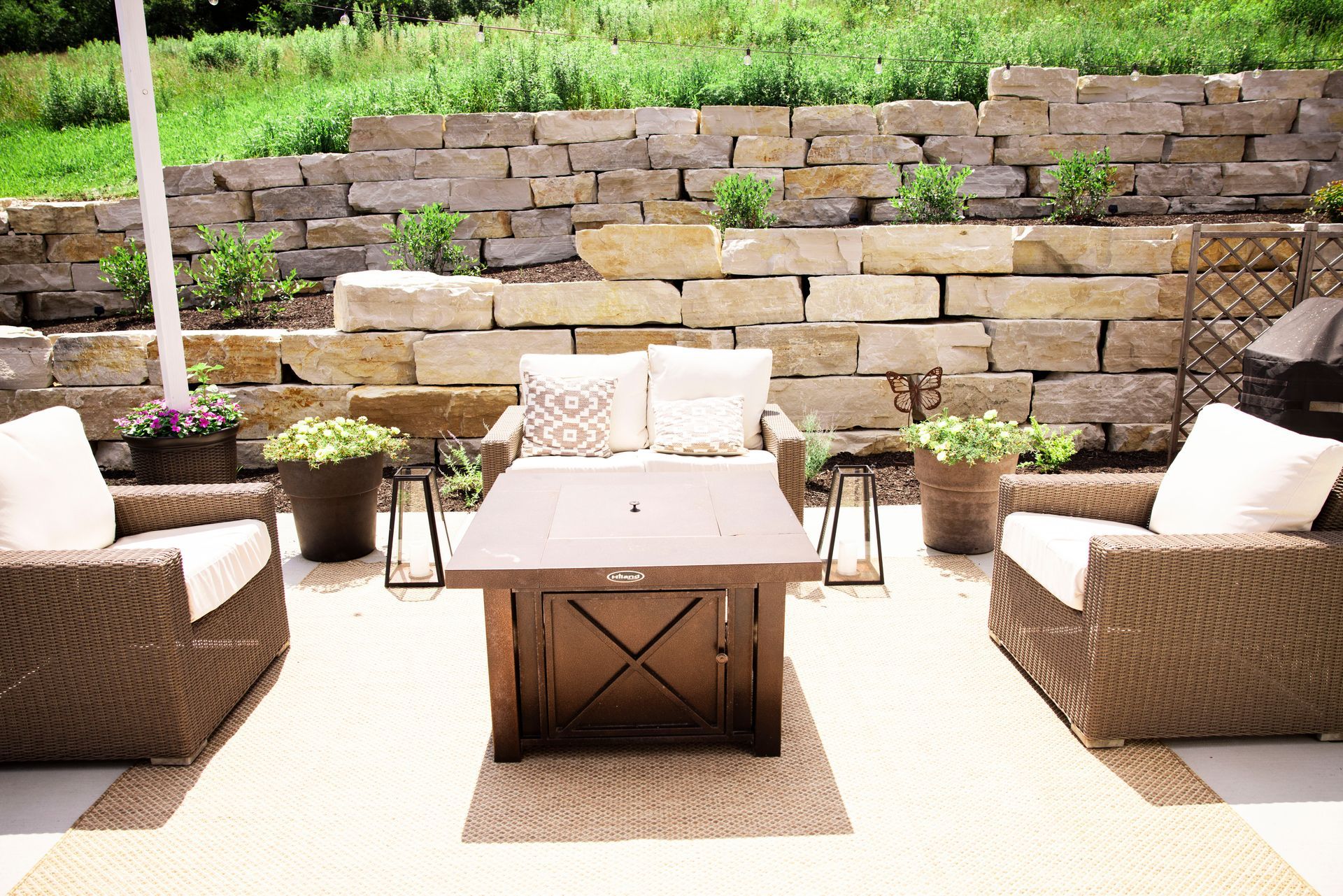 Outdoor patio with wicker furniture, a fire pit, and a stone wall.