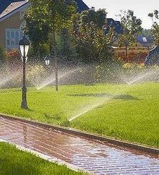 A sprinkler is spraying water on a lush green lawn.