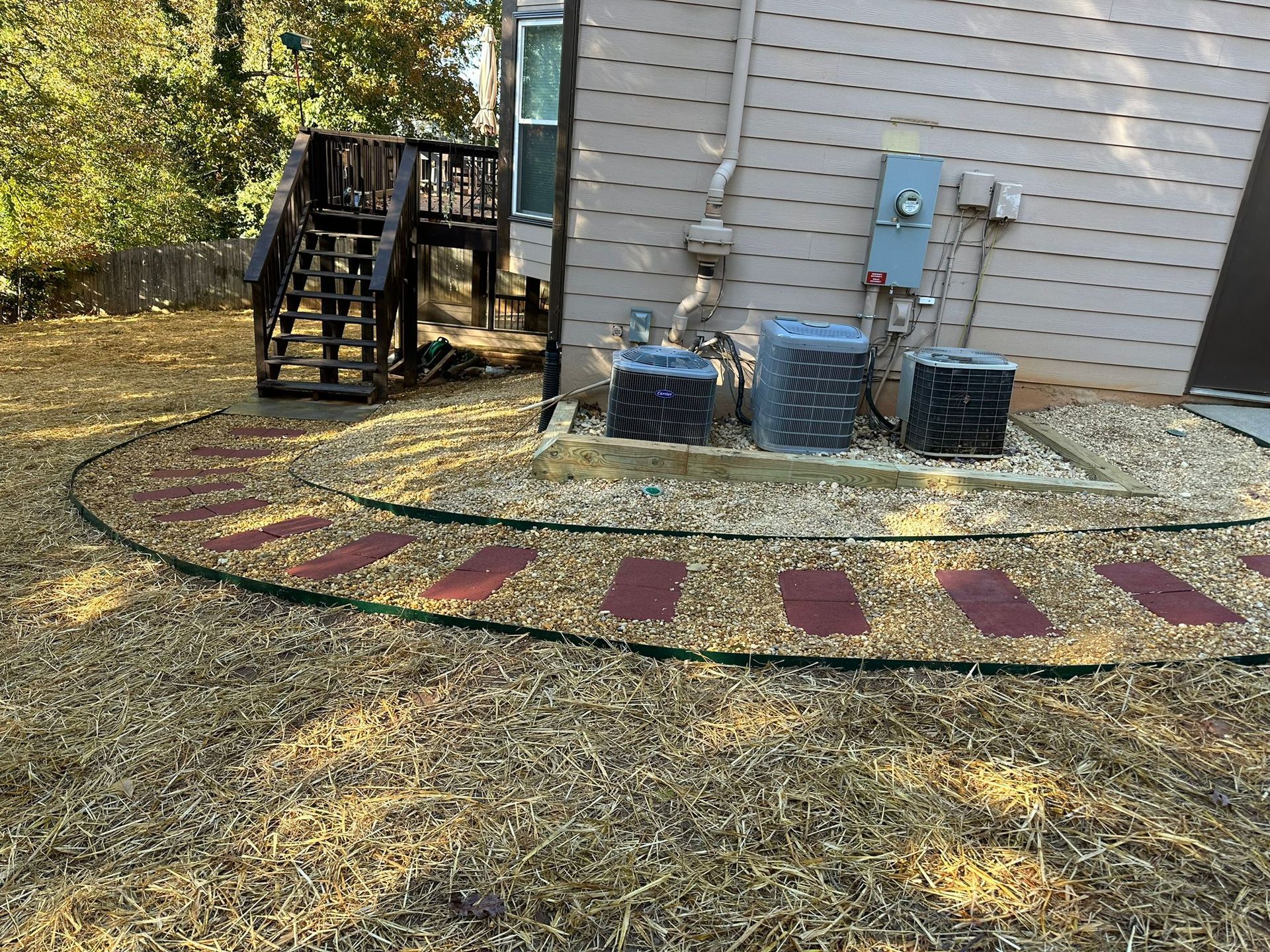 A backyard with a deck , stairs , and air conditioners.