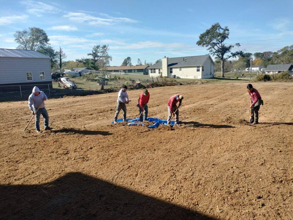 A group of people are working in a dirt field.