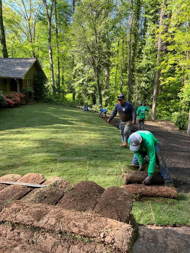 A group of men are working on a lush green lawn.