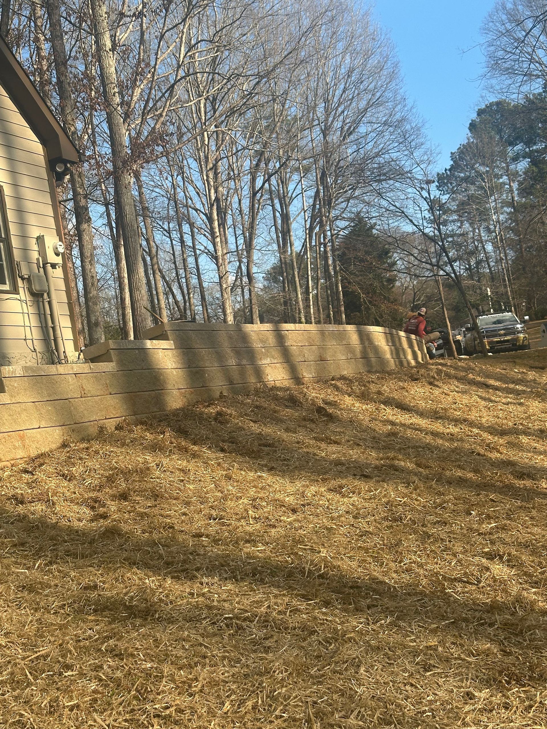 A house is sitting in the middle of a field with trees in the background.