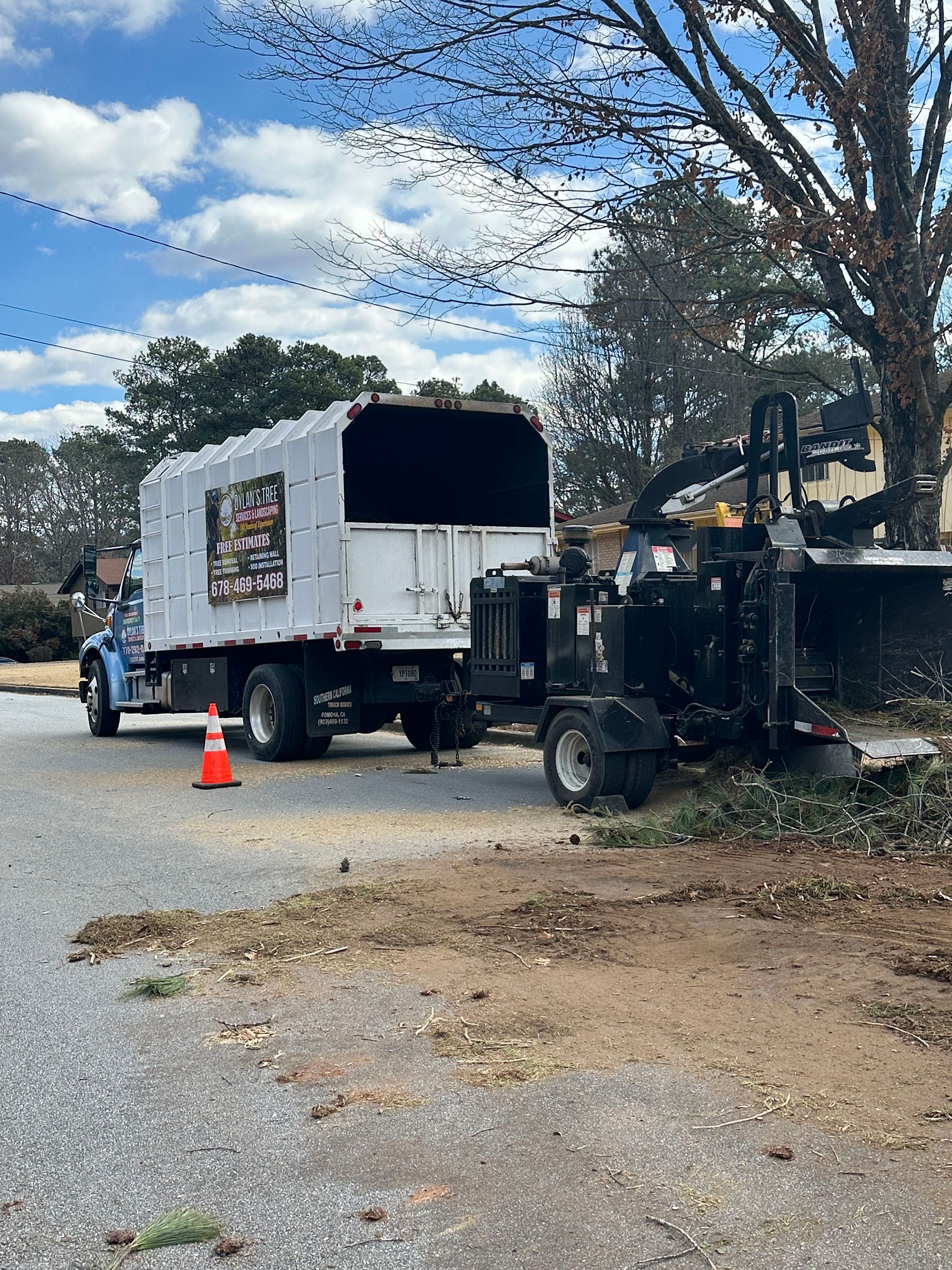 A truck is parked on the side of the road next to a tree chipper.