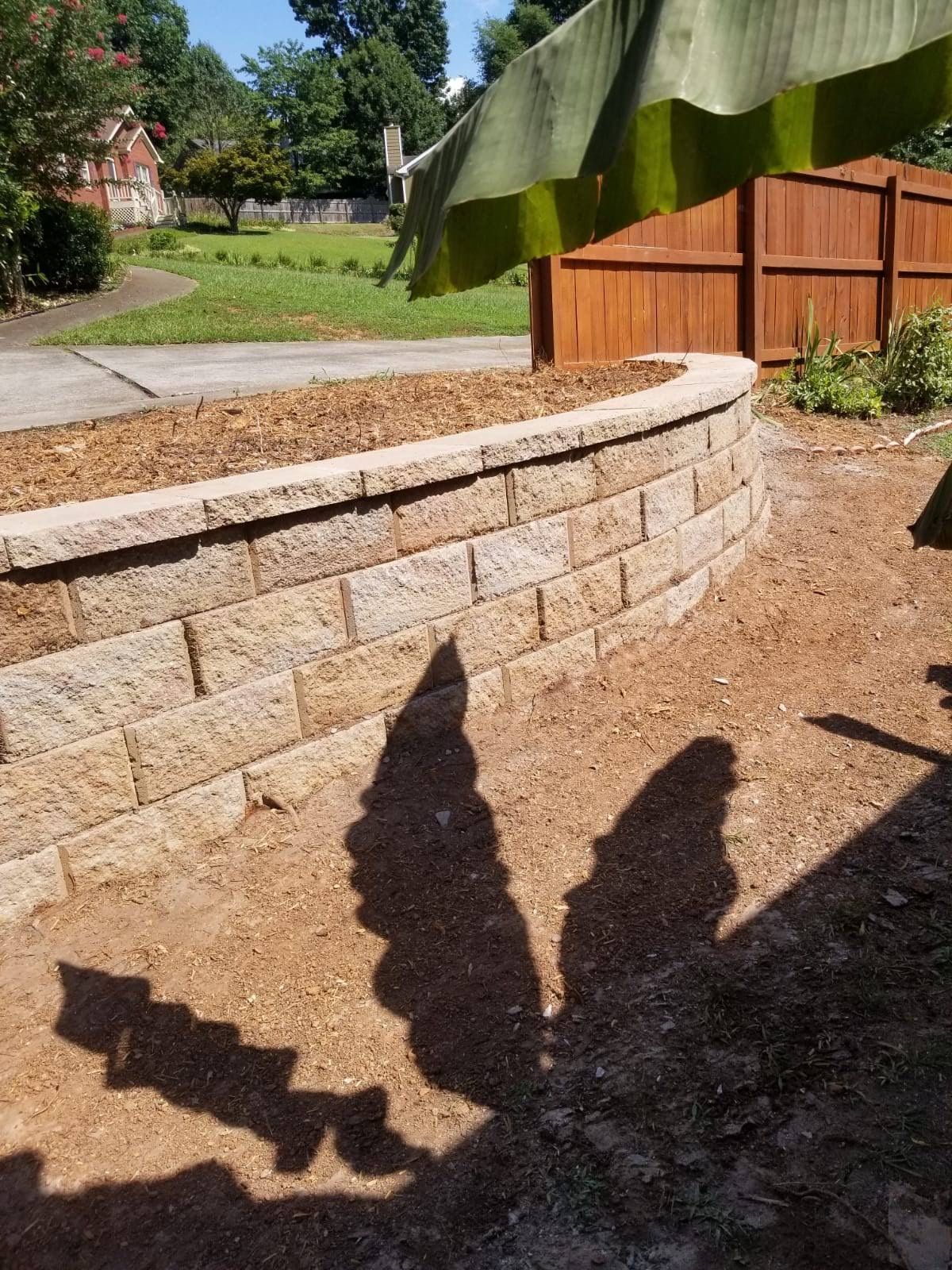 A shadow of a person is cast on a brick wall.