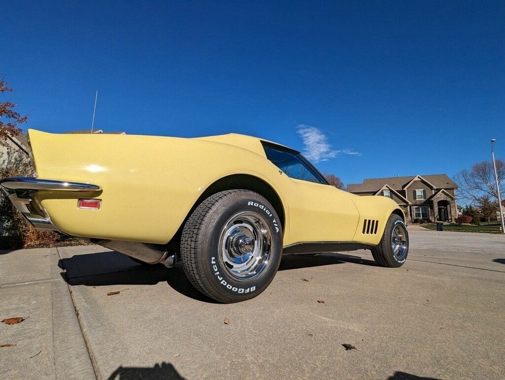 a yellow corvette is parked in a driveway in front of a house