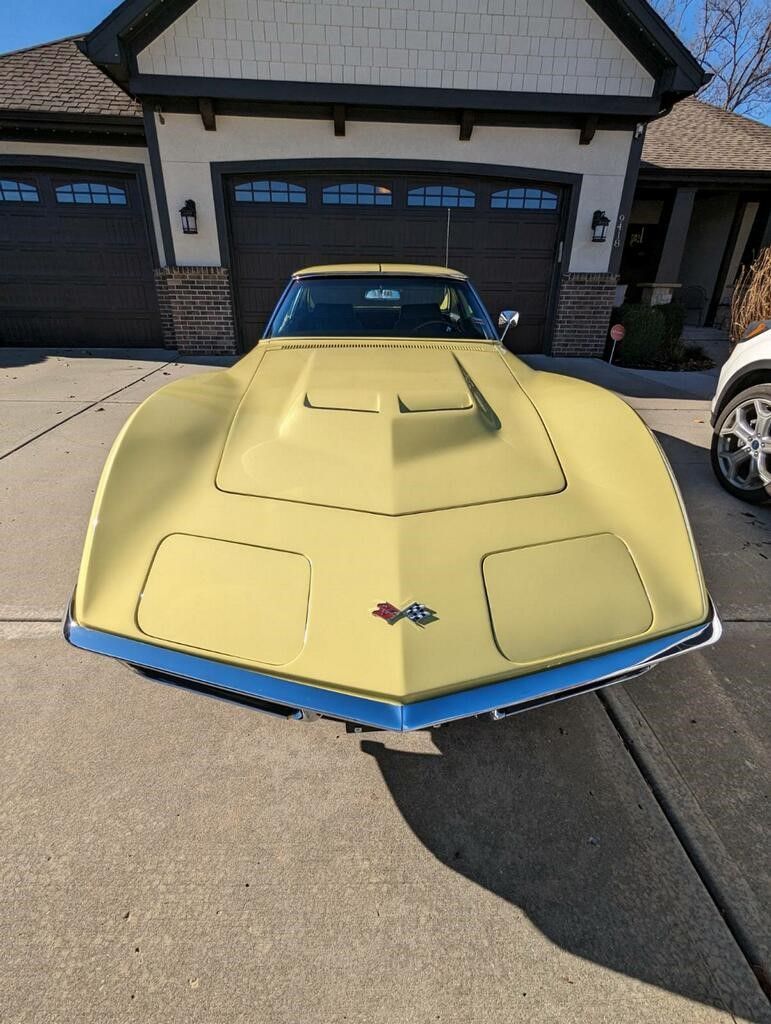 a yellow corvette is parked in front of a garage