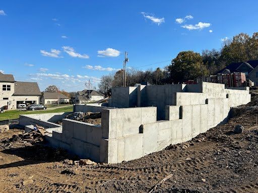 A large concrete wall is being built in a dirt field.