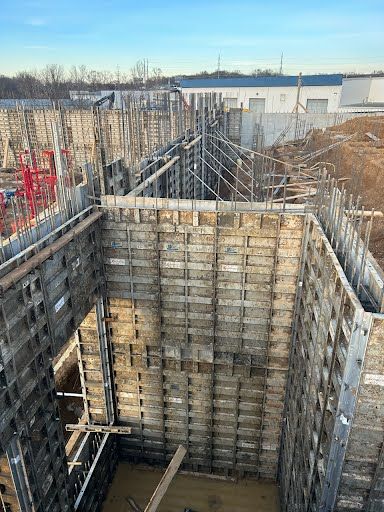 A large concrete wall is being built on a construction site.