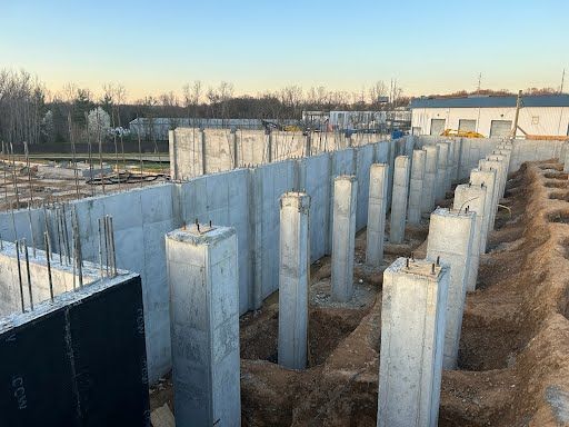 A large concrete wall is being built on a construction site.