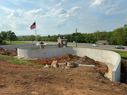 A large concrete wall is being built in front of a clock tower.
