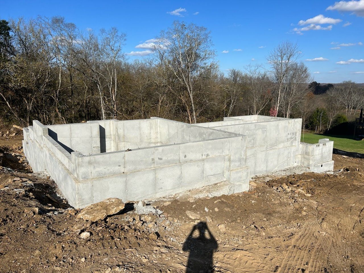 A concrete base for a house is being built in a dirt field.