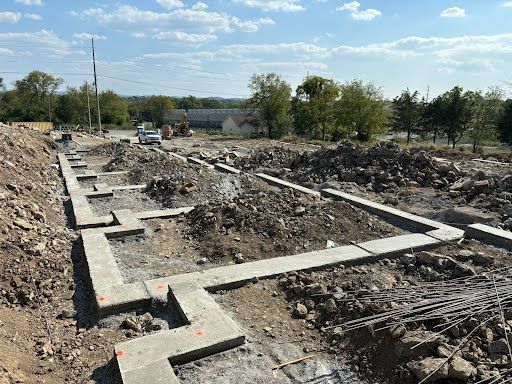 A construction site with a lot of dirt and concrete foundations.