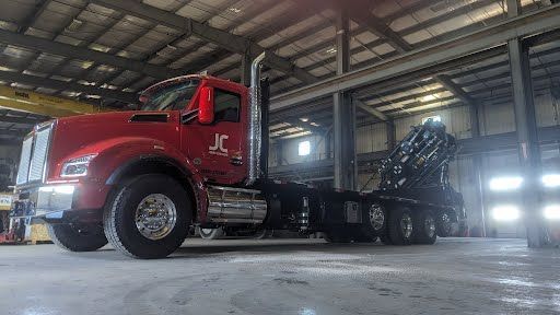 A red semi truck is parked in a warehouse.