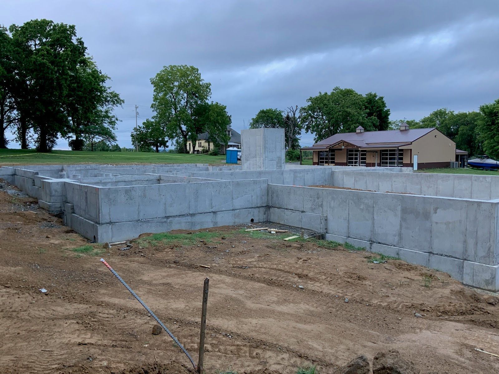 A concrete foundation is being built in a field with a house in the background.
