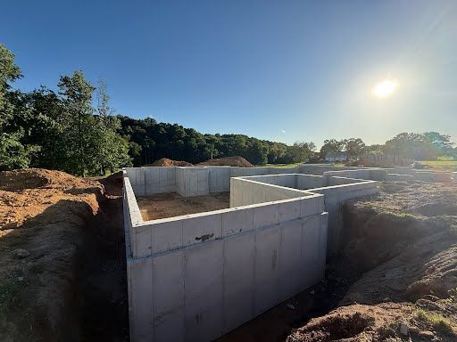 A concrete base for a house is being built in a dirt field.