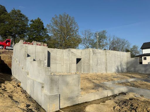A large concrete wall is being built next to a house.