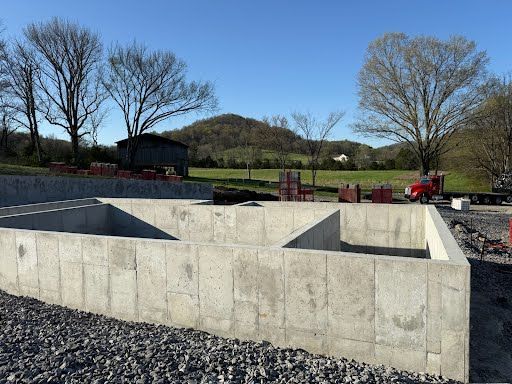 A concrete foundation is being built in a field with trees in the background.