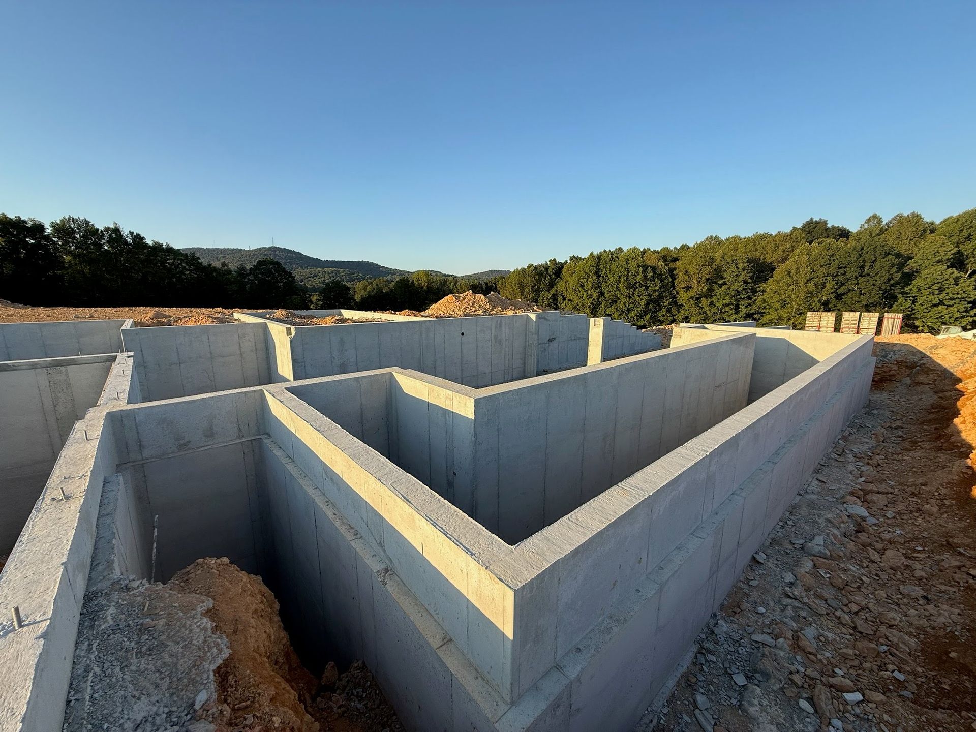 Concrete foundation walls of a house under construction, outdoors, under a blue sky.