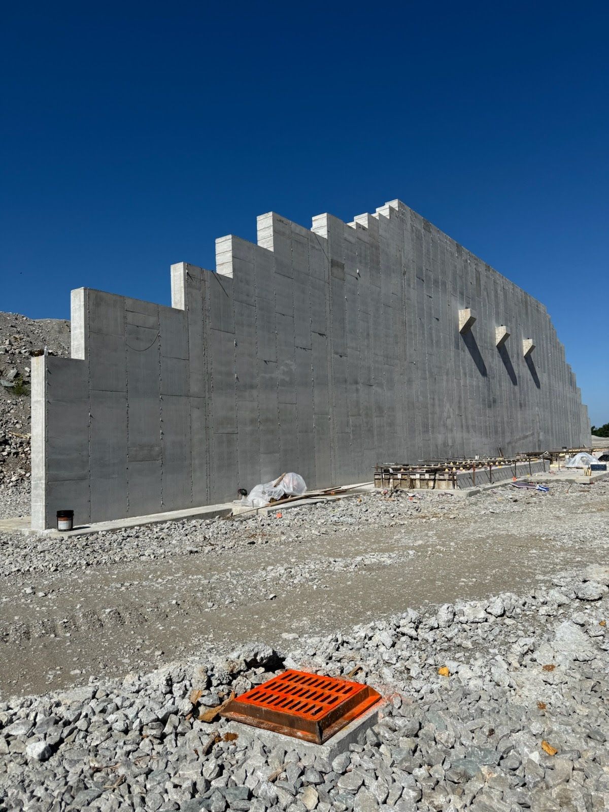 Concrete retaining wall under construction against a clear blue sky.