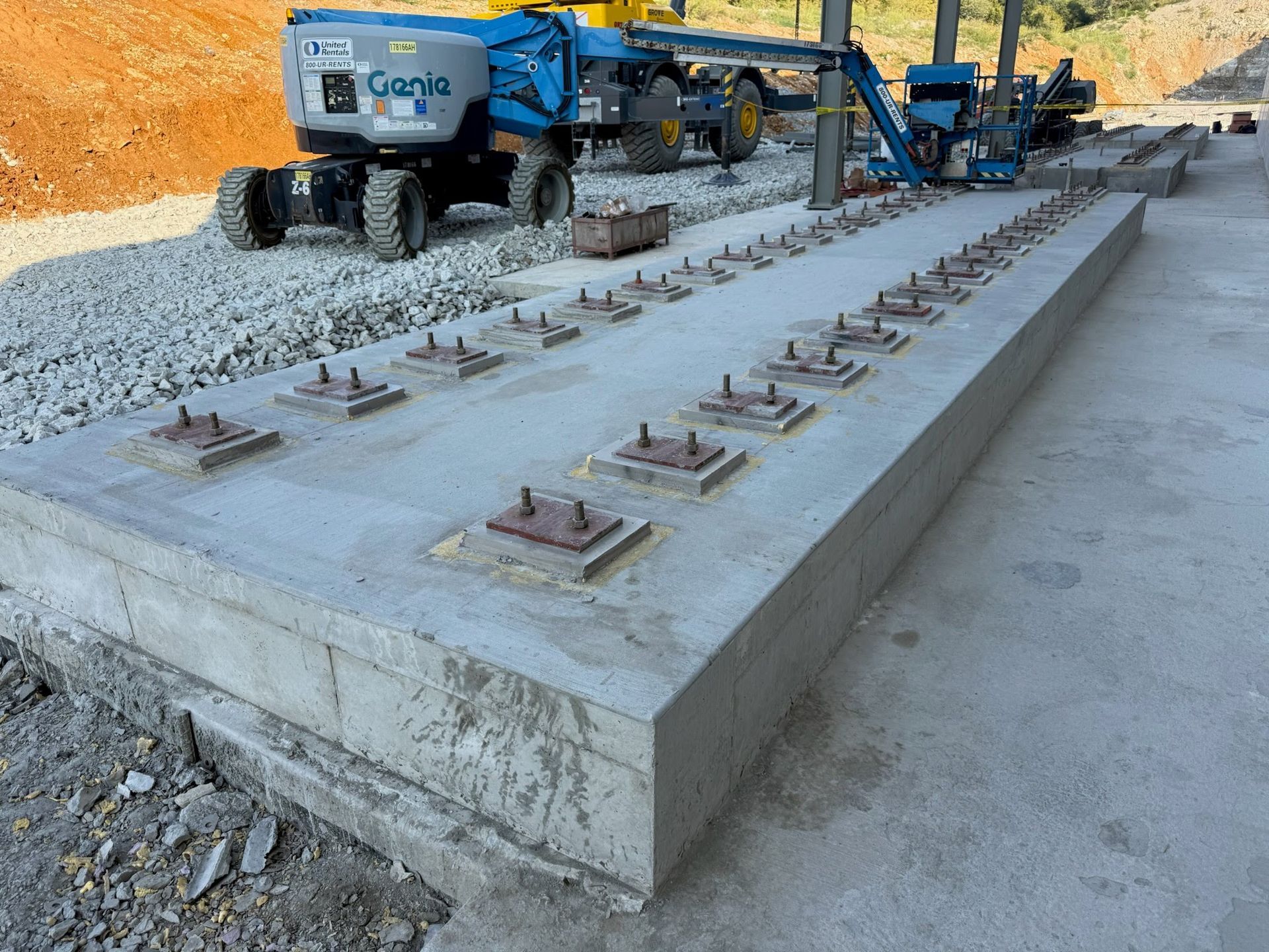 Concrete rail platform with metal fixtures, construction site, equipment in background.