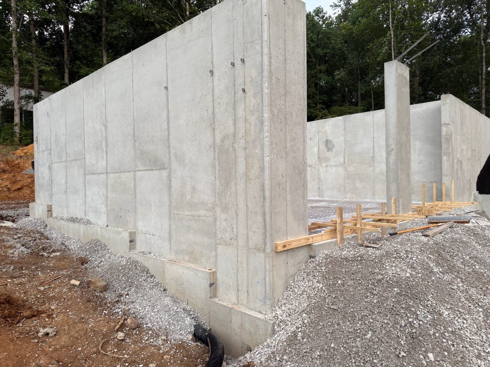 Concrete foundation walls under construction, with gravel and wooden supports.