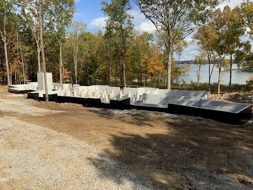 A large concrete structure is being built in the middle of a forest next to a lake.