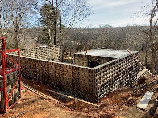 A large concrete wall is being built in the middle of a forest.