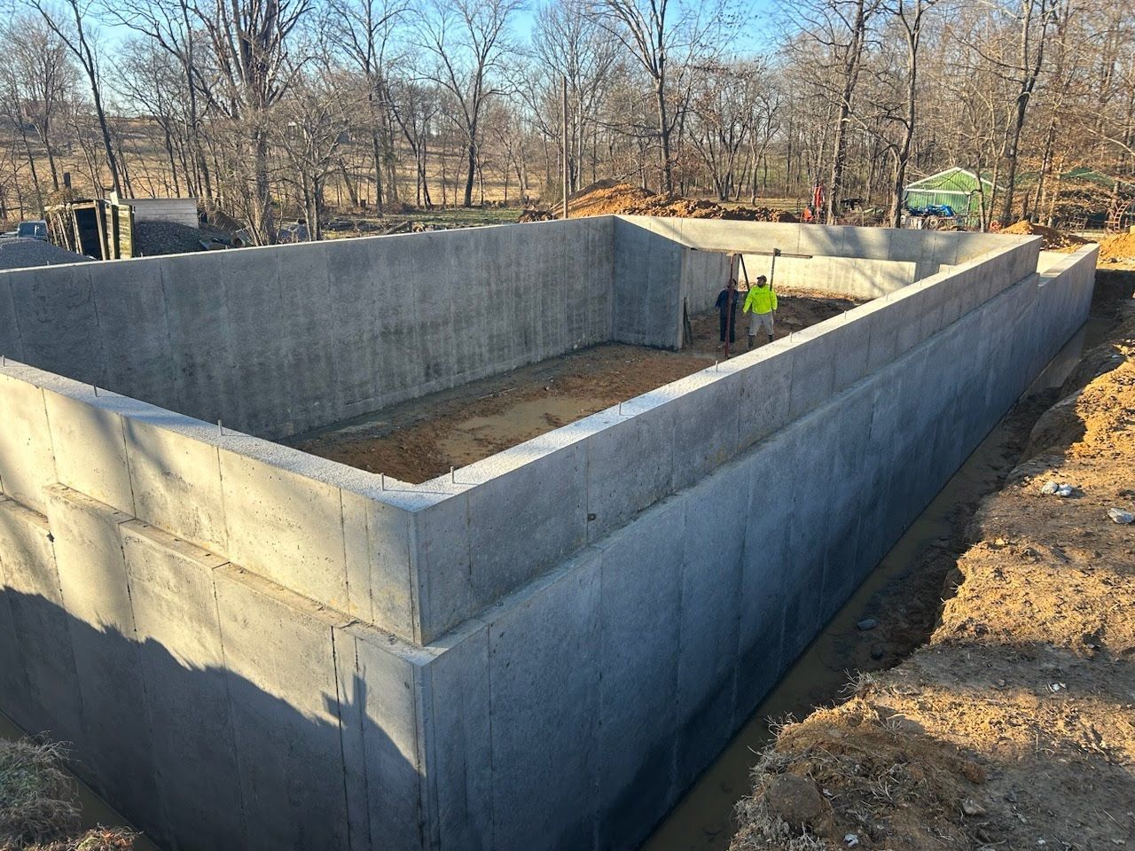 A large concrete wall is being built in the middle of a dirt field.