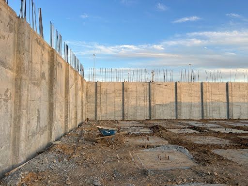 A large concrete wall is being built in a construction site.