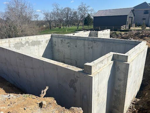 A large concrete wall is being built in front of a house.