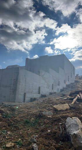 A large concrete building is being built on top of a dirt hill.