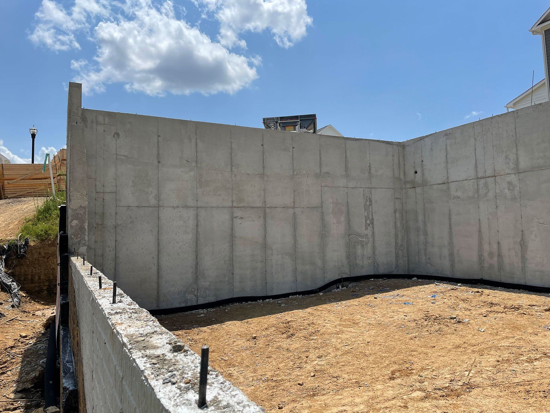 A large concrete wall is surrounding a dirt field.