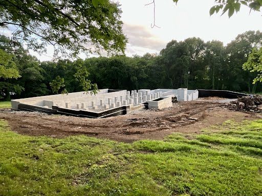 A house is being built in a field with trees in the background.