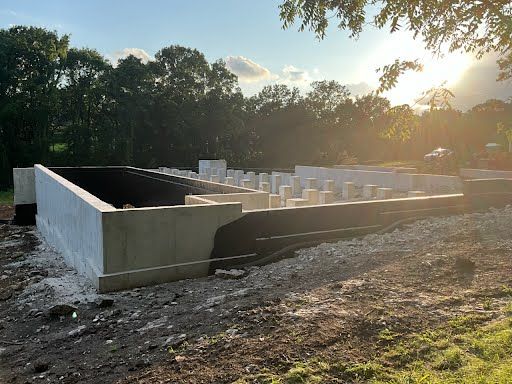 A large concrete wall is sitting in the middle of a dirt field.