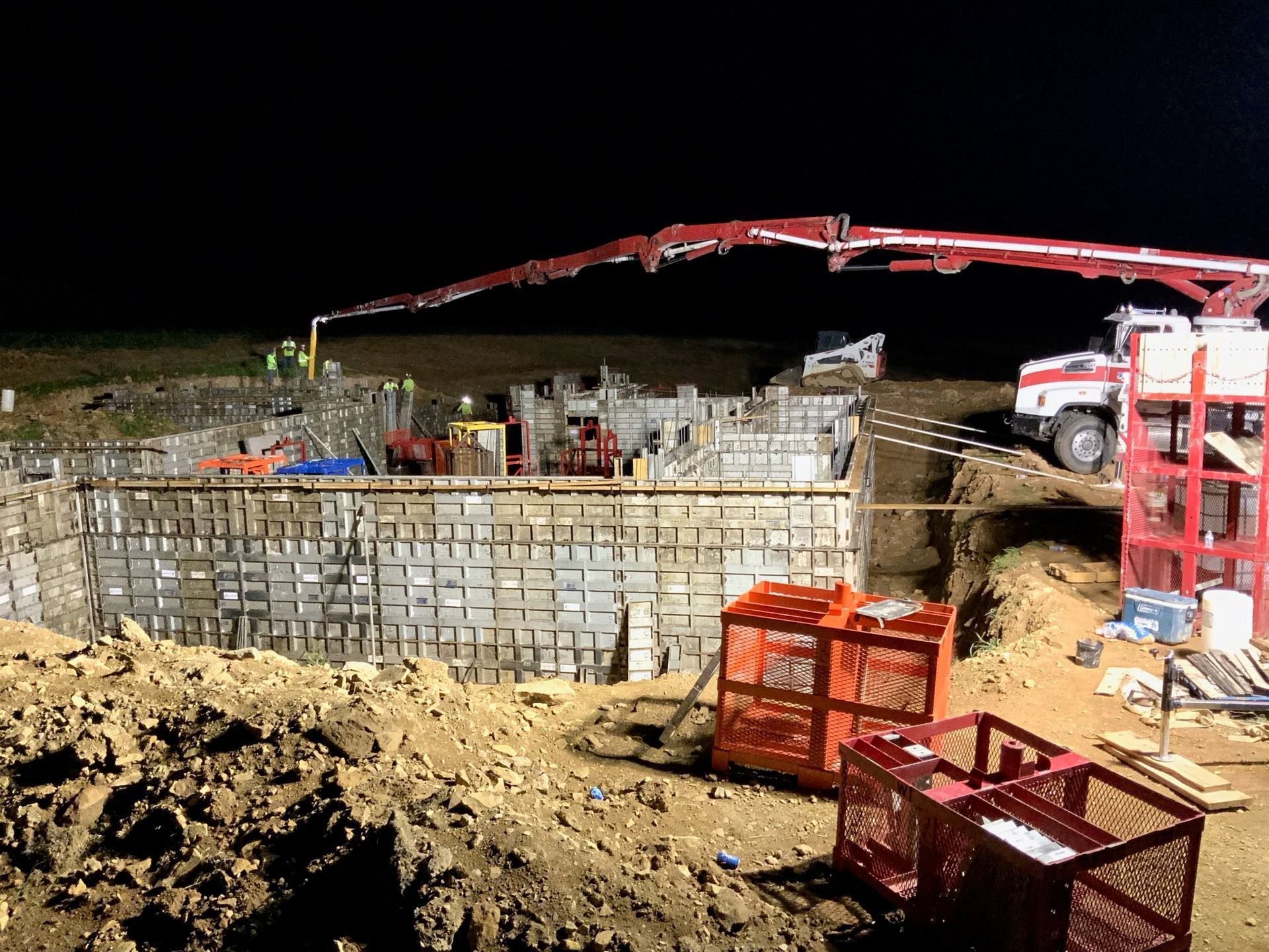 A construction site at night with a crane pumping concrete into the ground.