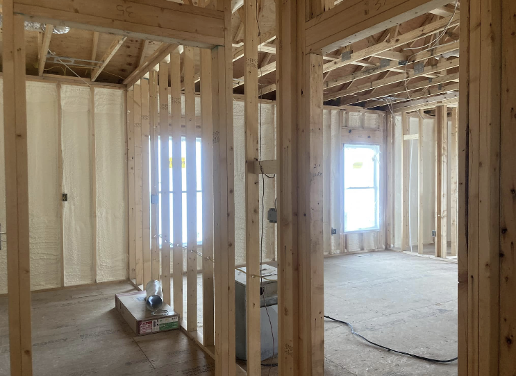 A room in a house under construction with wooden beams and a window.