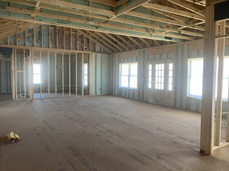An empty room in a house under construction with a lot of windows.