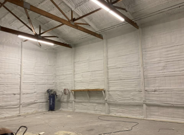 A large empty room with white walls and wooden beams.