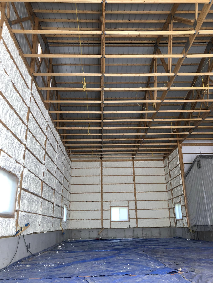 The inside of a large building with a blue tarp on the floor.