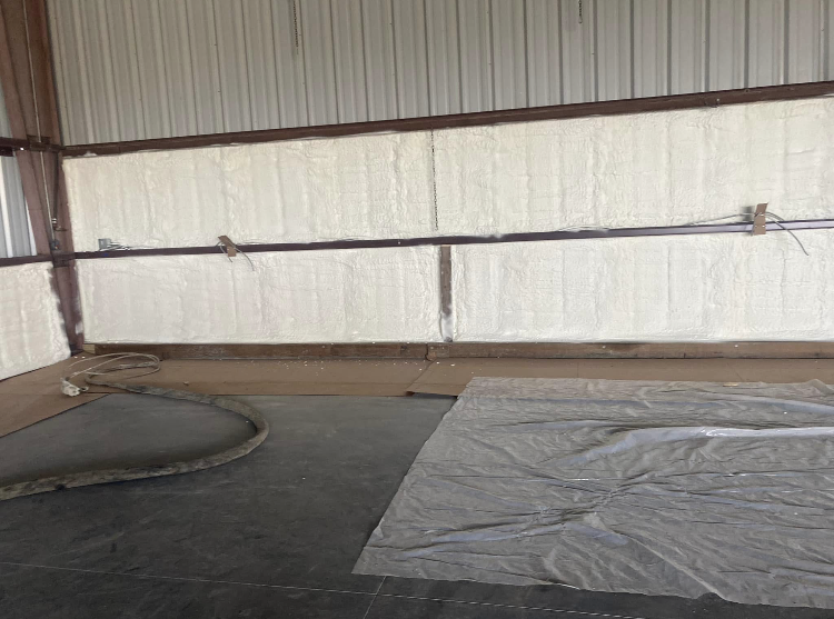 A room with a lot of insulation on the walls and a tarp on the floor.