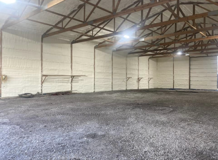 A large empty warehouse with a gravel floor and white walls.