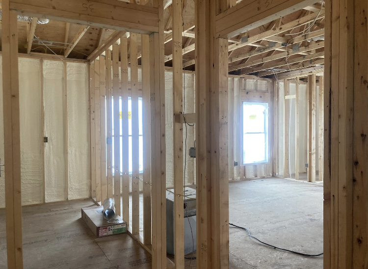 A room in a house under construction with wooden walls and a window.