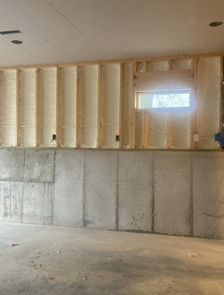 A basement under construction with concrete walls and a window.
