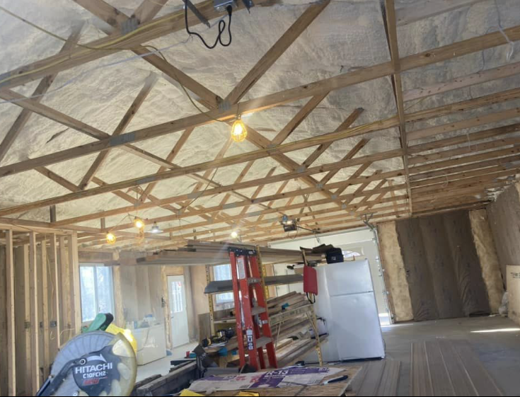A room under construction with a ladder and a refrigerator.