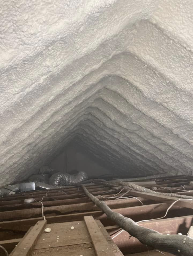 Looking up at the ceiling of an attic covered in spray foam.